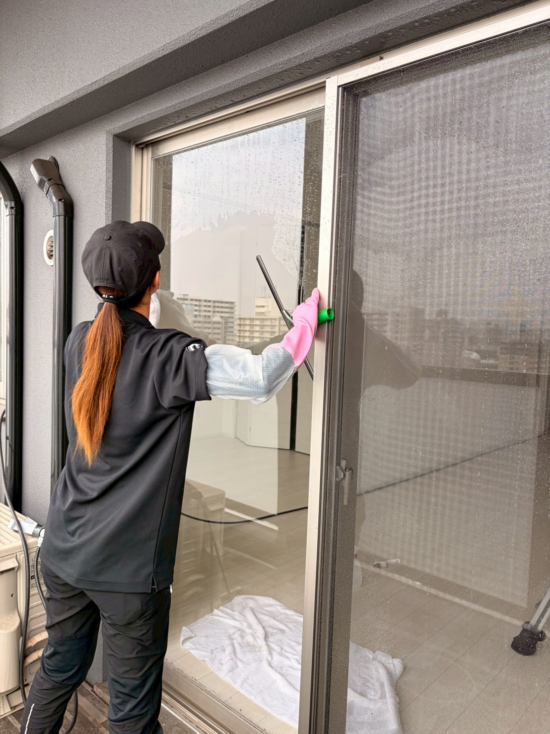 マンションの窓ガラスを丁寧に磨く縁の女性スタッフ